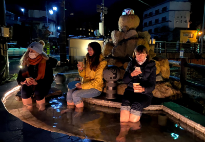 温かい飲み物を片手に足湯を楽しむ女性達