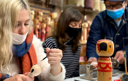 こけしの絵付け体験をしている女性